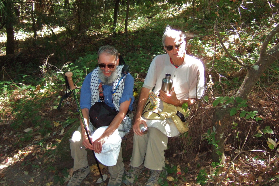 Frank rests his knee while David enjoys a snack and a drink on a convenient log.