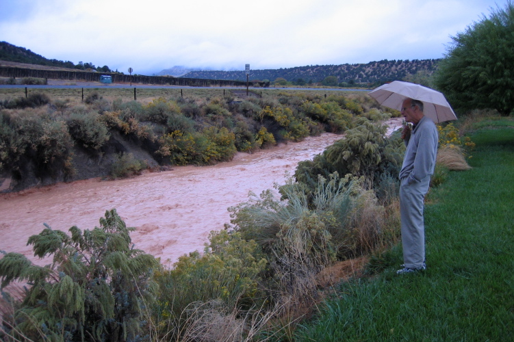 David watches water rush down the wash behind the hotel.