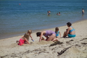The kids dig a deep hole with their bucket and spade.