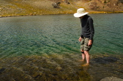 Bill takes a few tentative steps onto the hard, slimy rocks in the lake.