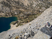 The terrain looks relatively smooth.  But, what cannot be seen from this vantage point (and what I failed to recall from our earlier traverse across the bottom of this face along the lake) are the cliffs that lie between us and the forest ahead.  Photo courtesy of Frank Paysen.