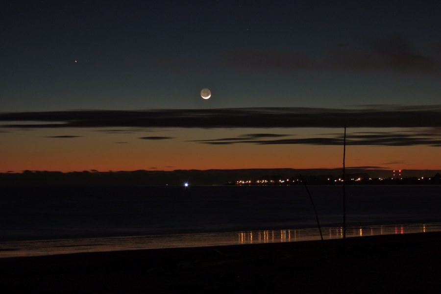 The waxing crescent follows the sun over the horizon.