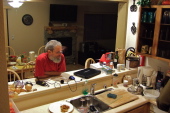 Frank watches David finish preparing salad.