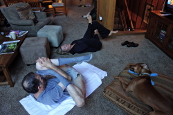 Bill touches his toes to his forehead while Laura tries.
