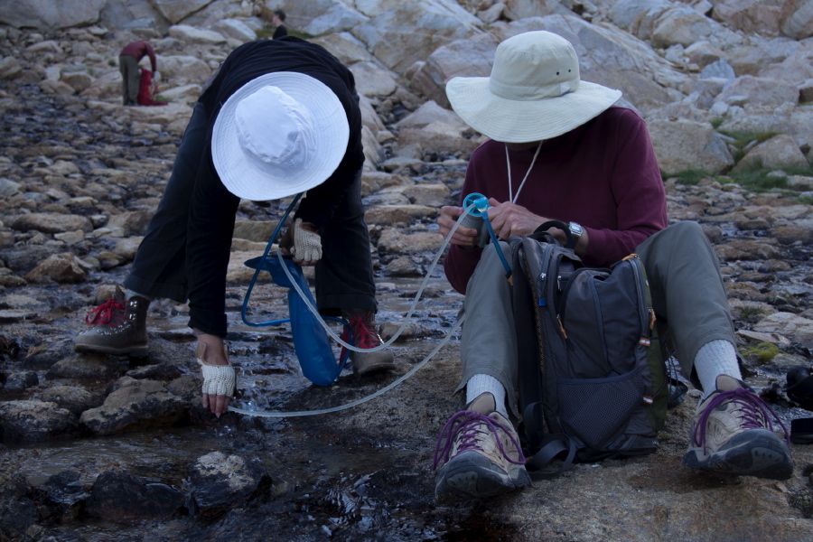 Stella and Bill pump water from the stream into a bladder.