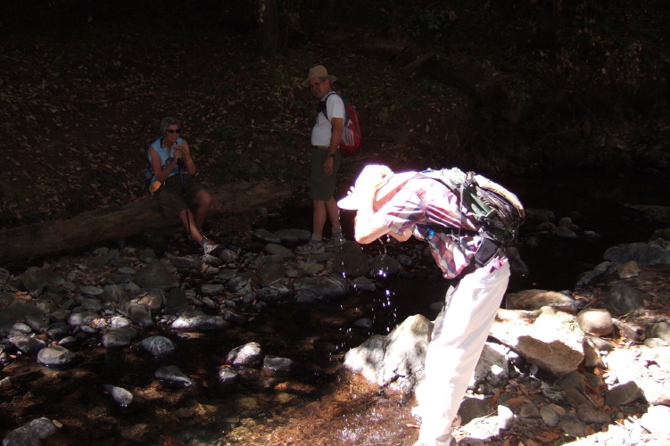 David soaks his hat in Peters Creek while Alice and Ron look on.