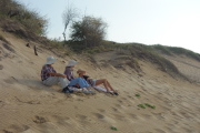 David, Kay, and Laura sit on a dune at Polihale State Beach near the barking sands