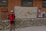 Frank stands in front of the large map on the wall of the store.