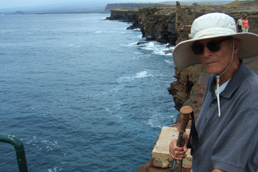 David stands atop the cliff at the water's edge.
