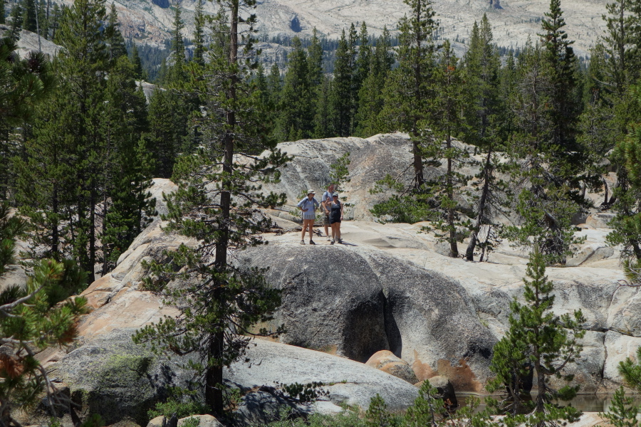 Hikers going the other way look for a way around the cliffs and ponds.