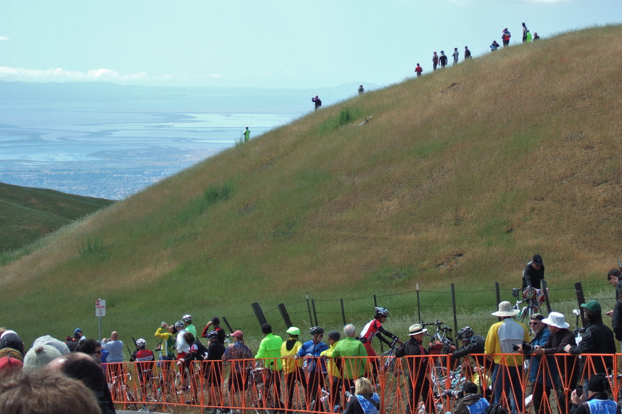 Spectators watch from atop a grassy knoll.