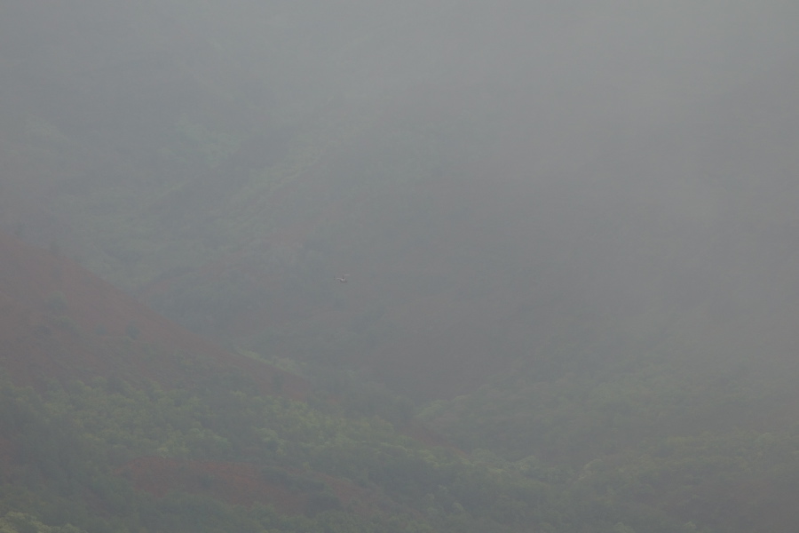 A helicopter can be glimpsed flying below the clouds.