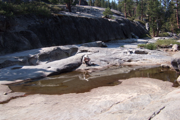 Bill pumping water from creek puddle.